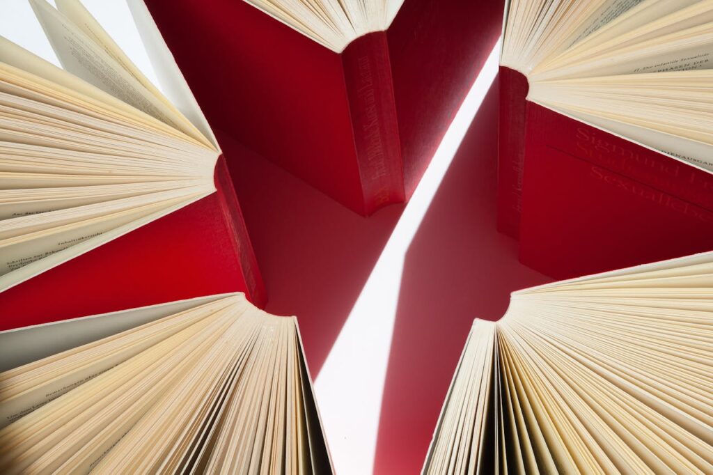 An artistic display of open books with red covers arranged in a star-like pattern.